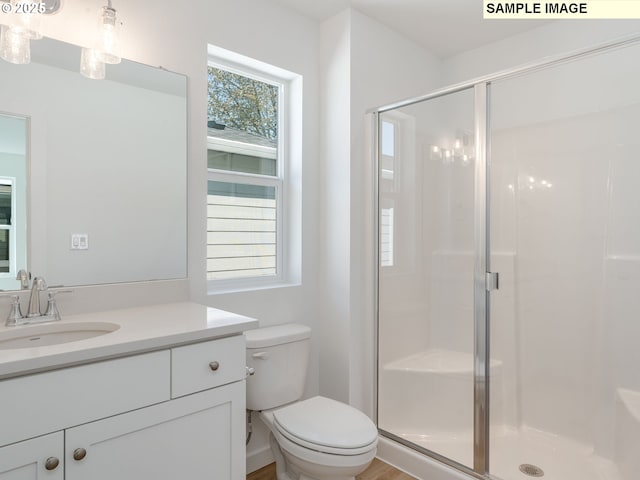full bathroom featuring a stall shower, toilet, and vanity