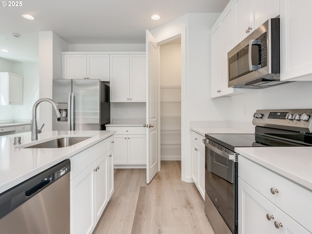 2307 SW 5th Pl, Battle Ground, WA 98604 - kitchen featuring appliances with stainless steel finishes, a sink, light wood-type flooring, recessed lighting, and white cabinets
