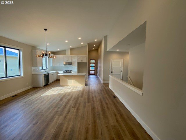 486 Meadows Dr, Manzanita, OR 97130 - kitchen with stainless steel dishwasher, light countertops, a chandelier, white cabinetry, and vaulted ceiling