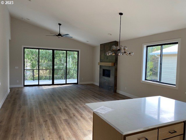 486 Meadows Dr, Manzanita, OR 97130 - unfurnished living room with healthy amount of natural light, a tiled fireplace, vaulted ceiling, wood finished floors, and ceiling fan