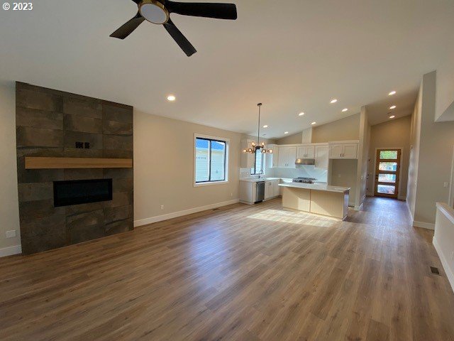 486 Meadows Dr, Manzanita, OR 97130 - unfurnished living room with lofted ceiling, a tile fireplace, a chandelier, recessed lighting, and a ceiling fan
