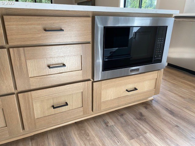 486 Meadows Dr, Manzanita, OR 97130 - kitchen view of stainless steel microwave, light brown cabinets, and dark wood-style flooring