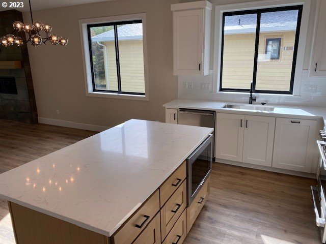 486 Meadows Dr, Manzanita, OR 97130 - kitchen featuring stainless steel appliances, light wood-type flooring, white cabinets, and a center island