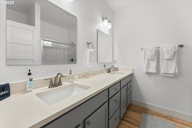 531 NW Vancouver Ave, Stevenson, WA 98648 - bathroom featuring double vanity, a shower with shower door, wood finished floors, and baseboards