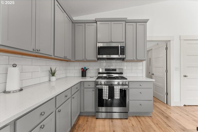 531 NW Vancouver Ave, Stevenson, WA 98648 - kitchen featuring appliances with stainless steel finishes, gray cabinetry, light wood-style flooring, and vaulted ceiling
