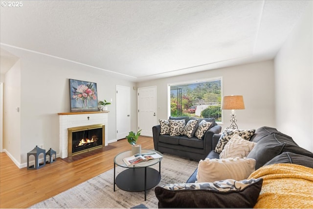 living area featuring wood finished floors, a fireplace, baseboards, and a textured ceiling
