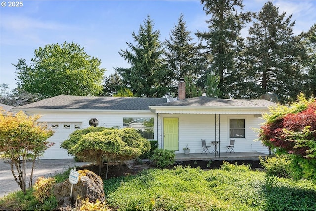 view of front of property with a garage, a chimney, and a porch