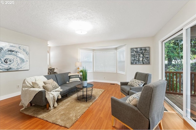 living room with wood finished floors, healthy amount of natural light, baseboards, and a textured ceiling