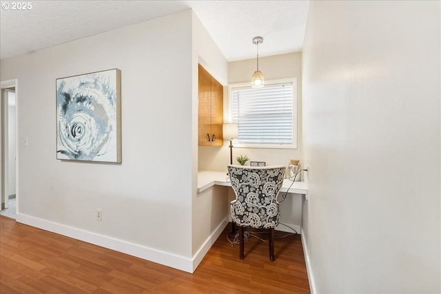 corridor featuring wood finished floors, baseboards, and a desk