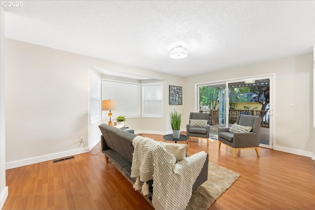 living area with baseboards, wood finished floors, and a textured ceiling