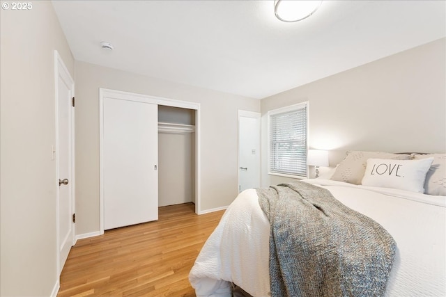 bedroom featuring light wood finished floors, baseboards, and a closet