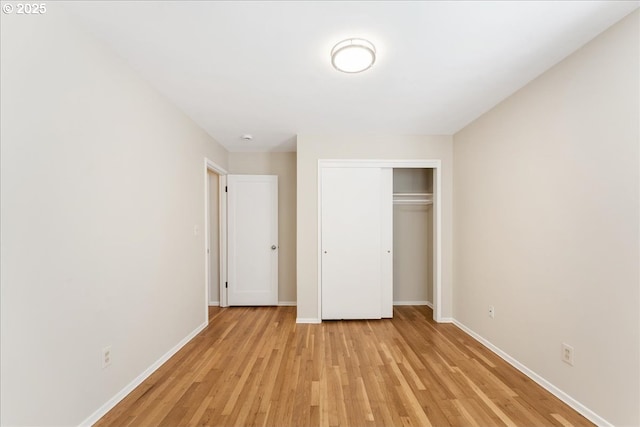 unfurnished bedroom with light wood-style floors, baseboards, and a closet