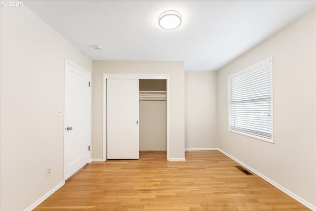 unfurnished bedroom featuring light wood-style floors, a closet, and baseboards