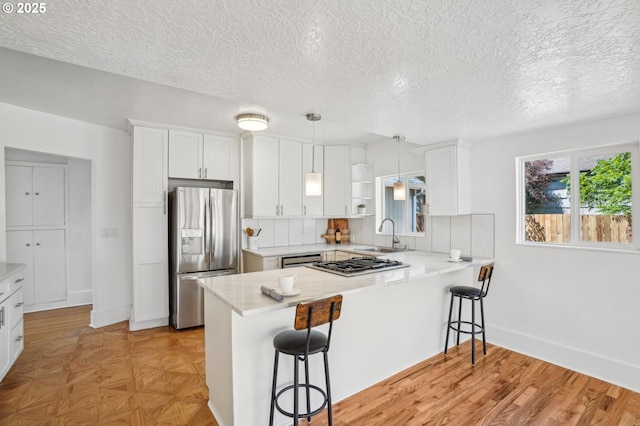 1952 SE 139th Ave, Portland, OR 97233 - kitchen with appliances with stainless steel finishes, a sink, a peninsula, a textured ceiling, and white cabinets
