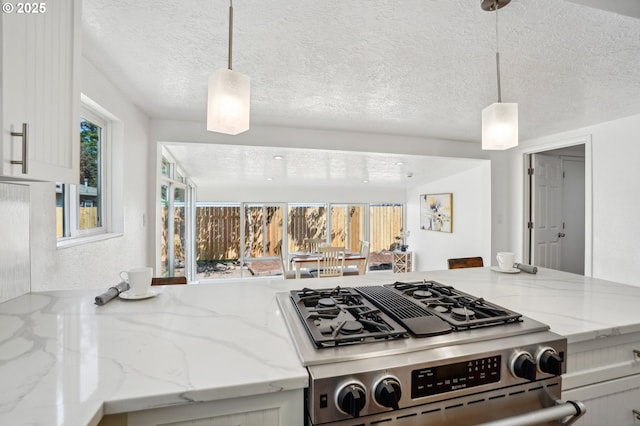 1952 SE 139th Ave, Portland, OR 97233 - kitchen with stainless steel gas range oven, white cabinets, light stone counters, pendant lighting, and a textured ceiling