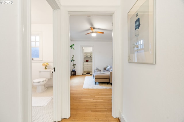 corridor featuring ornamental molding, light wood finished floors, and baseboards