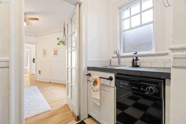 bar featuring black dishwasher, backsplash, ornamental molding, light wood-style floors, and a sink