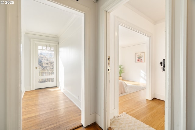 hallway with ornamental molding, baseboards, and wood finished floors