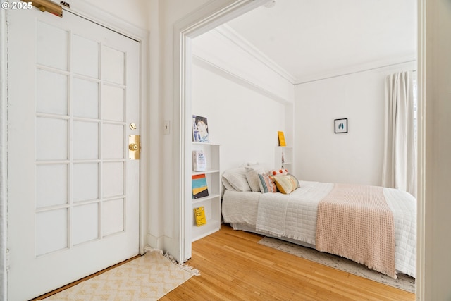 bedroom featuring crown molding and light wood-style floors