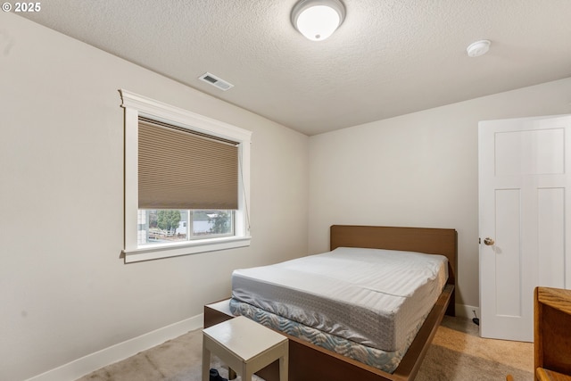 bedroom with a textured ceiling and light colored carpet