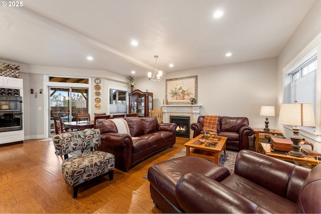 living room with a chandelier, beam ceiling, and light wood-type flooring