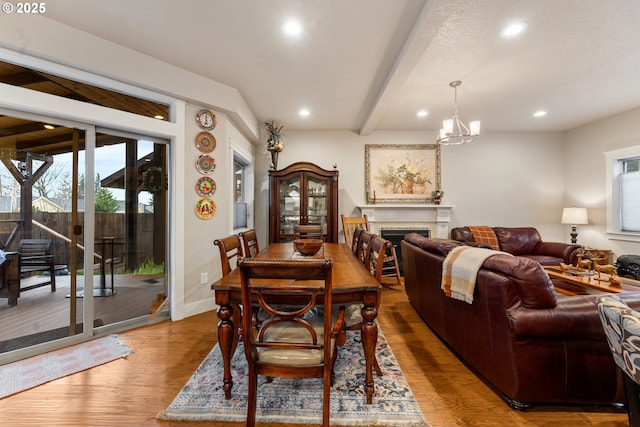 dining room with a chandelier, beam ceiling, and light hardwood / wood-style flooring