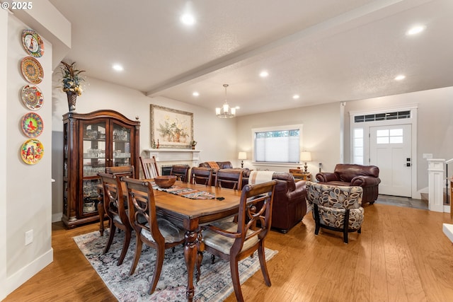 dining space with a chandelier, beam ceiling, and light hardwood / wood-style floors