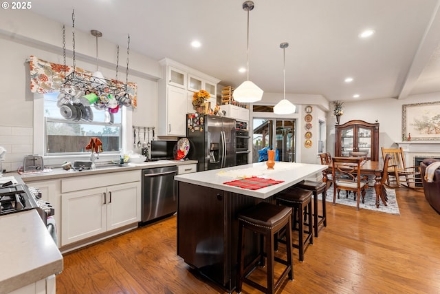 kitchen featuring white cabinetry, a healthy amount of sunlight, hanging light fixtures, stainless steel appliances, and a kitchen island