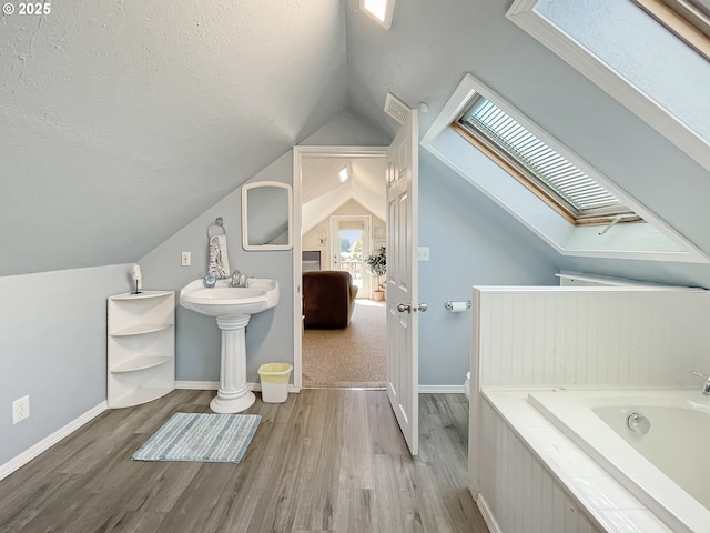97994 W Benham Ln, Brookings, OR 97415 - bathroom with a skylight, wood finished floors, a bath, lofted ceiling, and a textured ceiling