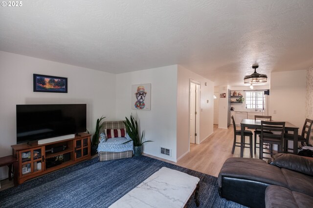 living area with a textured ceiling, baseboards, and wood finished floors