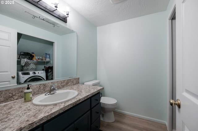 bathroom featuring washer / dryer, wood finished floors, toilet, vanity, and baseboards