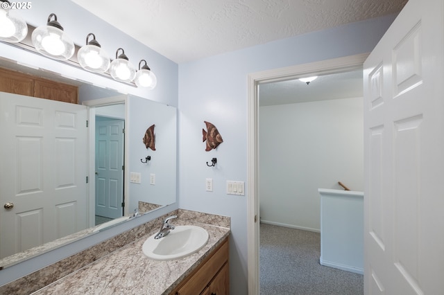bathroom featuring vanity, a textured ceiling, and baseboards