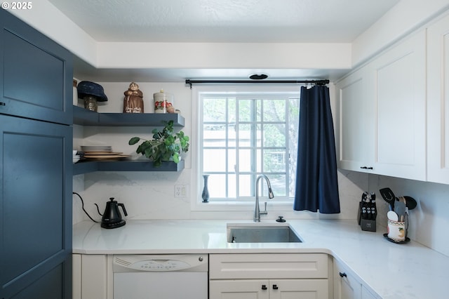 kitchen with white dishwasher, a sink, and white cabinetry
