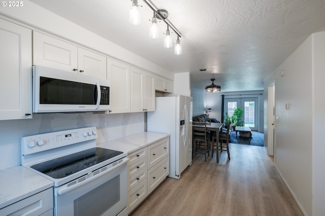 kitchen featuring white appliances, light wood-type flooring, white cabinetry, french doors, and a textured ceiling