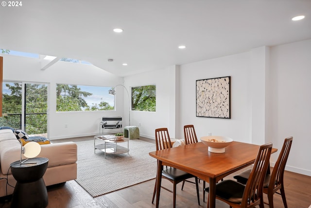 dining space with plenty of natural light, wood-type flooring, and vaulted ceiling