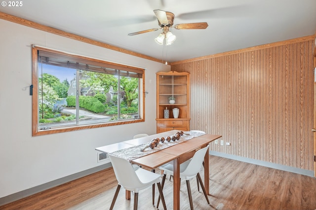 5955 NE 32nd Ave, Portland, OR 97211 - dining area with a ceiling fan, baseboards, wood walls, and light wood-style flooring