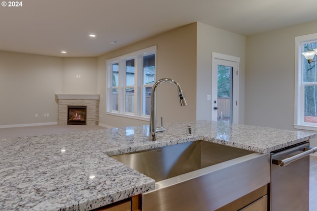 kitchen with sink, light stone countertops, and stainless steel dishwasher