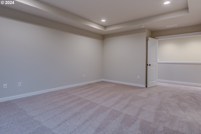 carpeted spare room featuring a tray ceiling