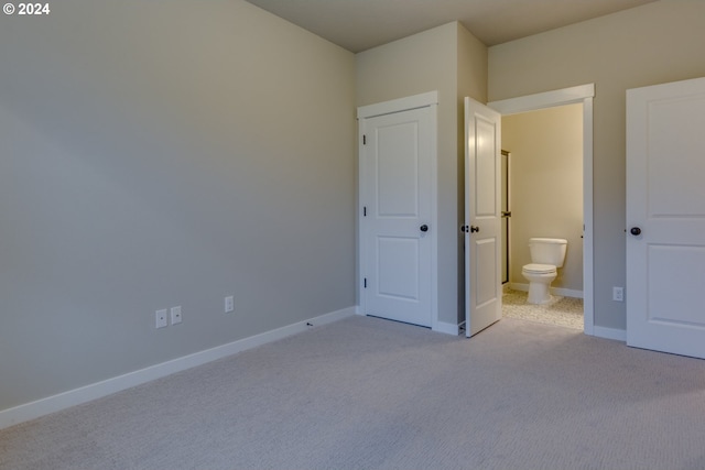 unfurnished bedroom featuring light colored carpet and ensuite bath