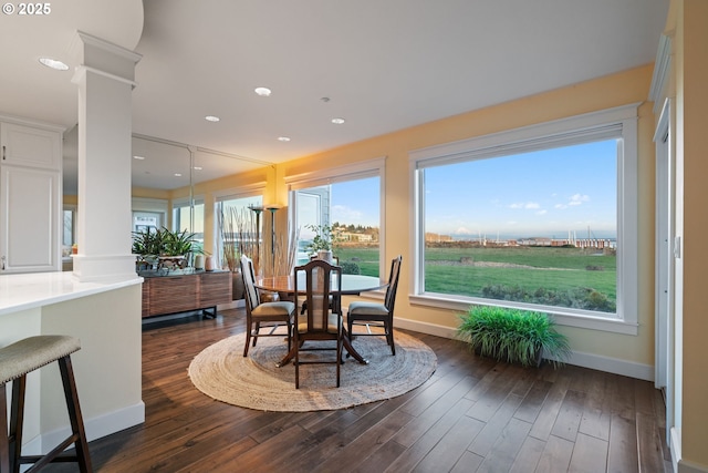 dining room featuring dark wood finished floors, baseboards, and ornate columns