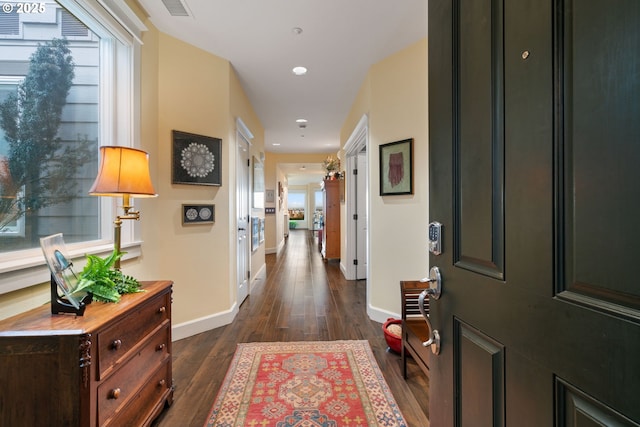 hallway with recessed lighting, visible vents, baseboards, and dark wood-style floors