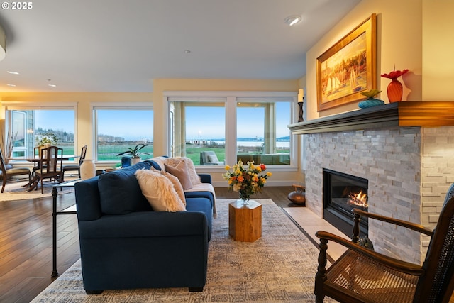 living room featuring recessed lighting, wood-type flooring, a healthy amount of sunlight, and a fireplace