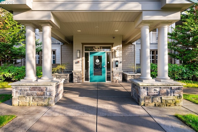 entrance to property featuring elevator, stone siding, and a porch