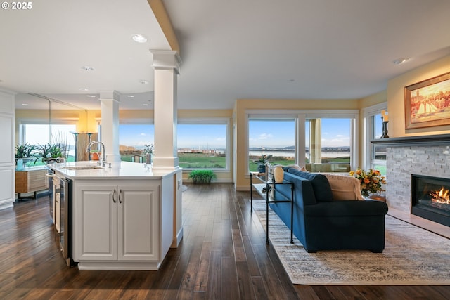 kitchen with open floor plan, light countertops, decorative columns, a fireplace, and a sink