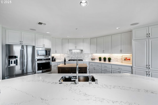 kitchen with visible vents, tasteful backsplash, appliances with stainless steel finishes, and a sink