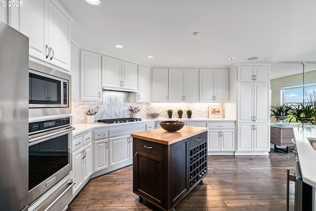 kitchen featuring stainless steel appliances, dark wood-type flooring, white cabinets, wood counters, and a warming drawer