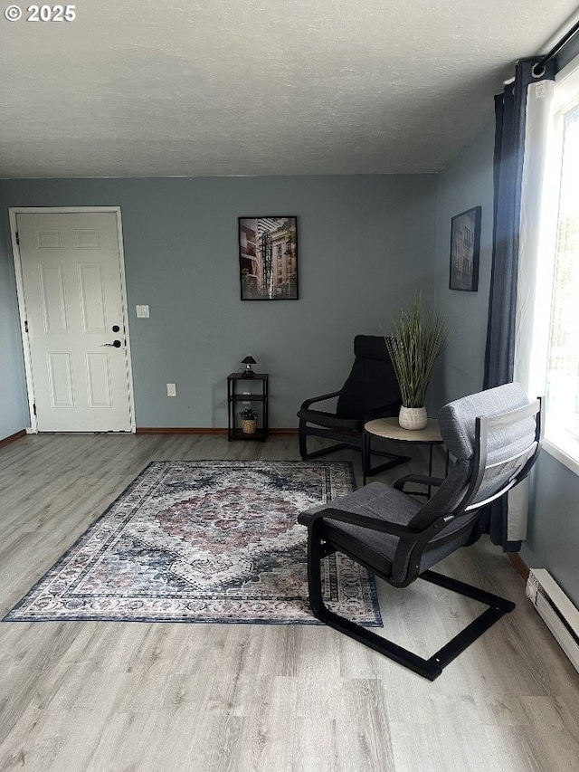 living area with baseboard heating, wood finished floors, and baseboards