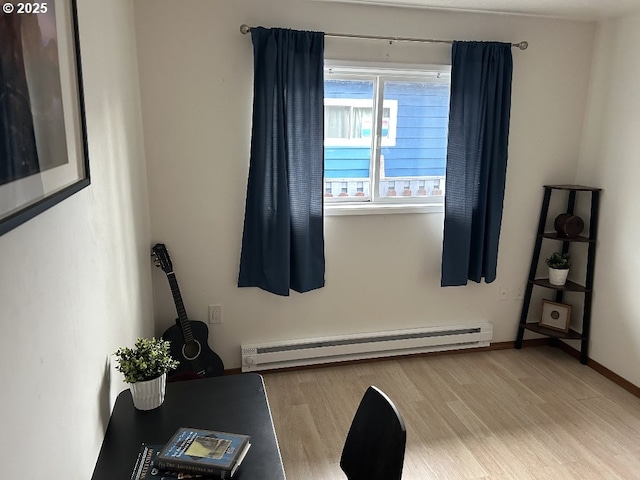 workout area featuring a baseboard radiator, wood finished floors, and baseboards