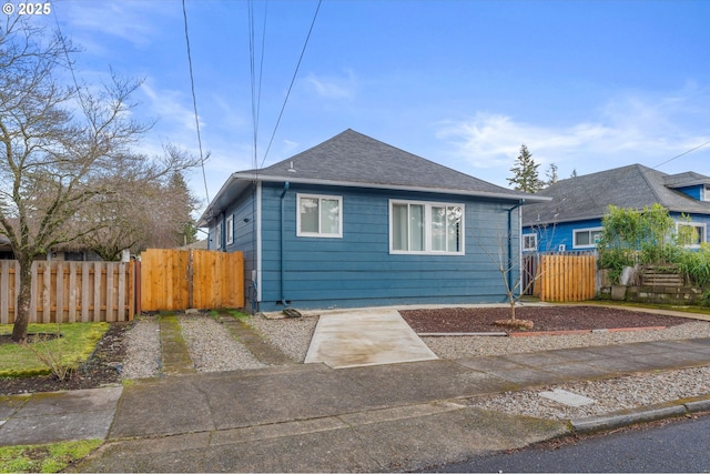bungalow-style home with fence and a shingled roof