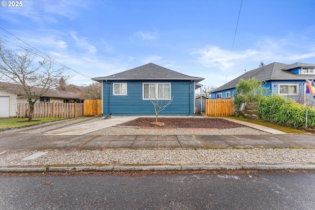 bungalow featuring fence, driveway, and a shingled roof